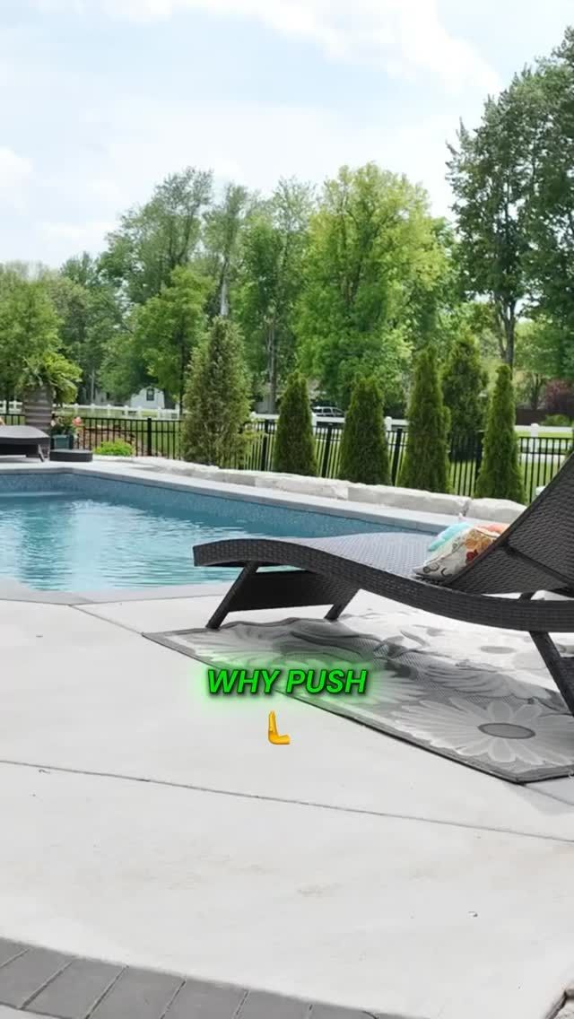 Poolside scene with a chaise lounge and a pool with trees in the background. 