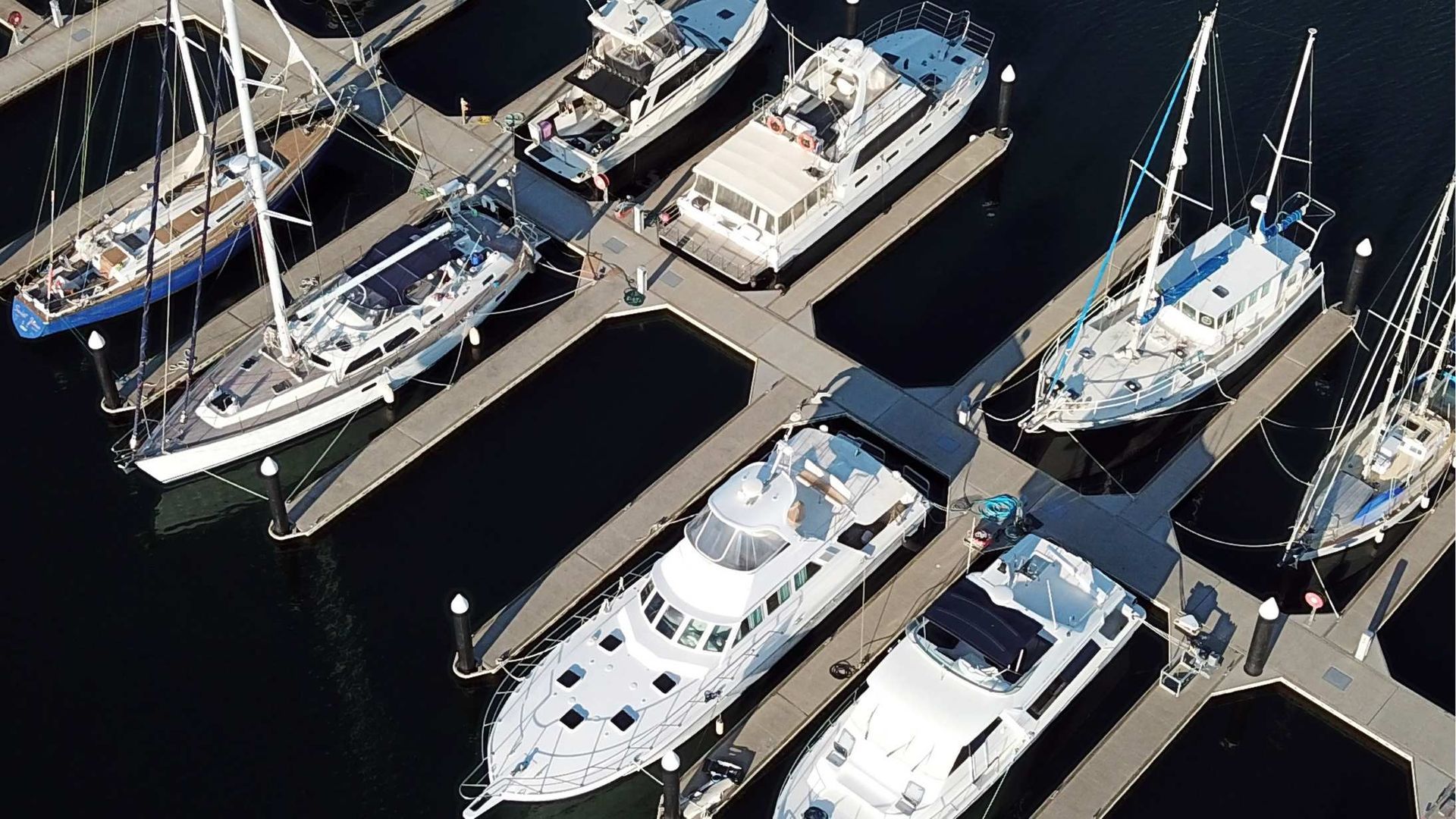 Aerial view of docked boats at a marina. Boats of various sizes and styles are lined up along piers.