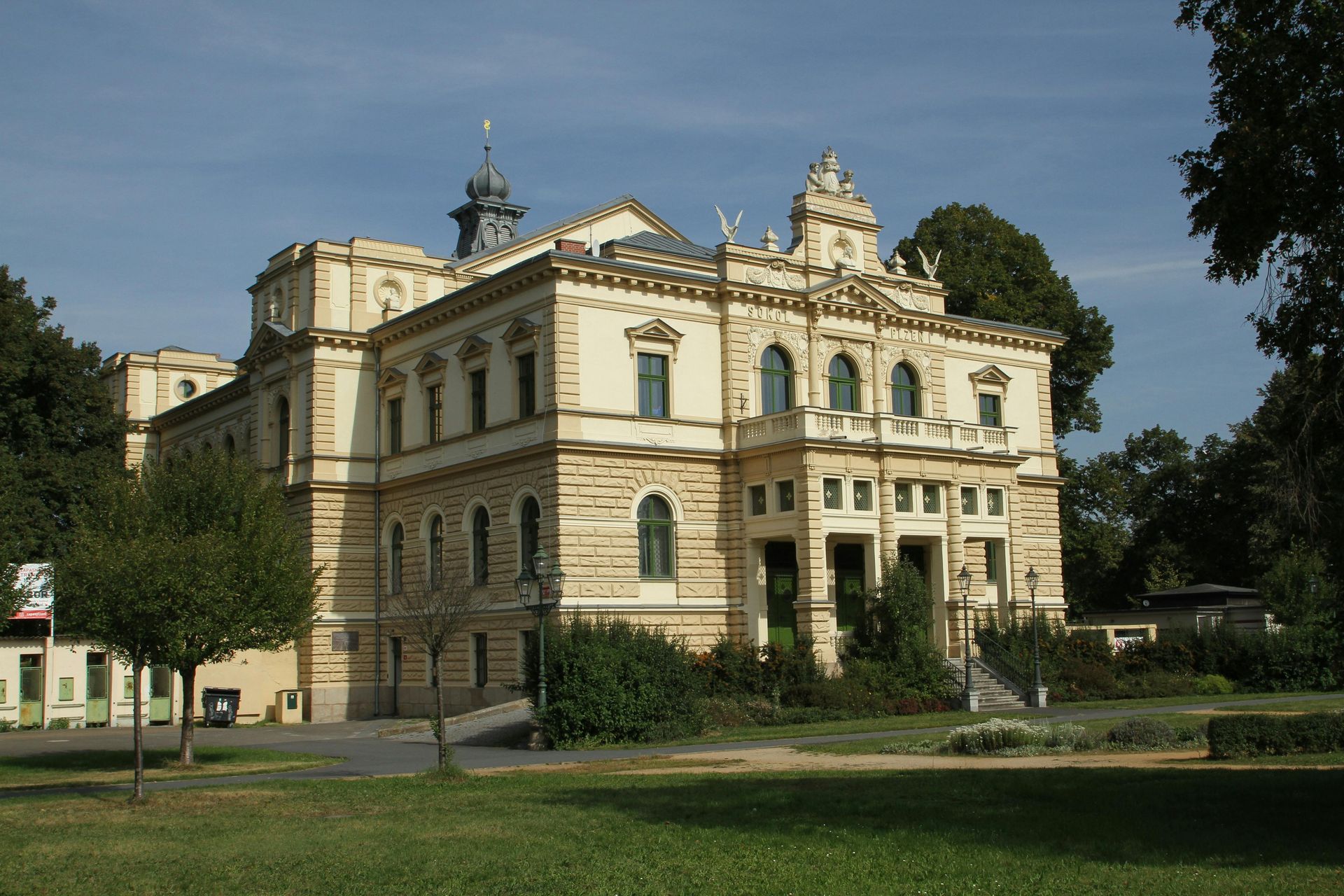 Large beige two-story house with a pool. The pool is turquoise, and there is a patio area with seating.