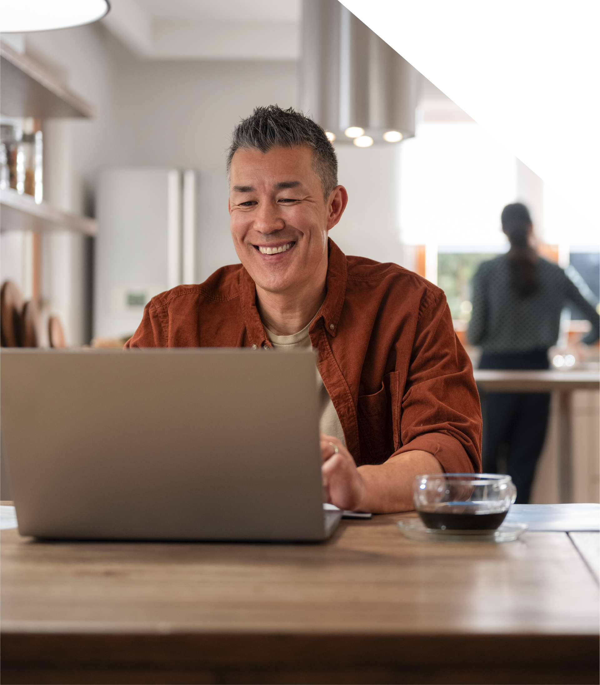 A man is sitting at a table using a laptop computer.