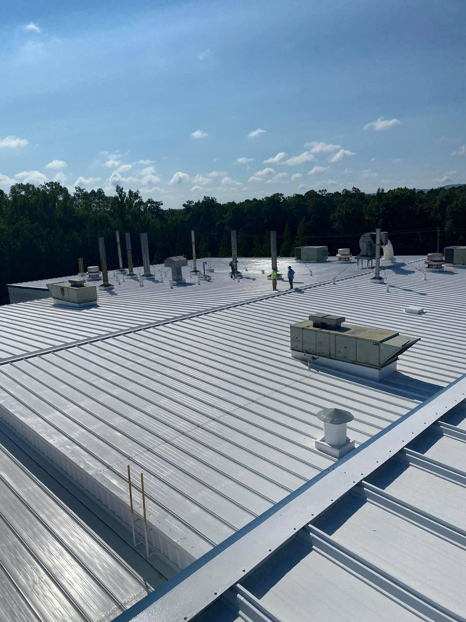 The roof of a building with a white roof and trees in the background.