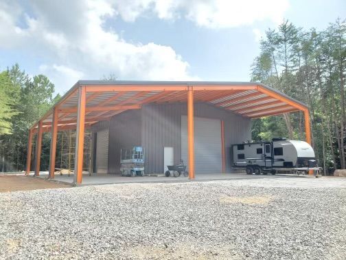 A large metal building with a trailer parked underneath it.