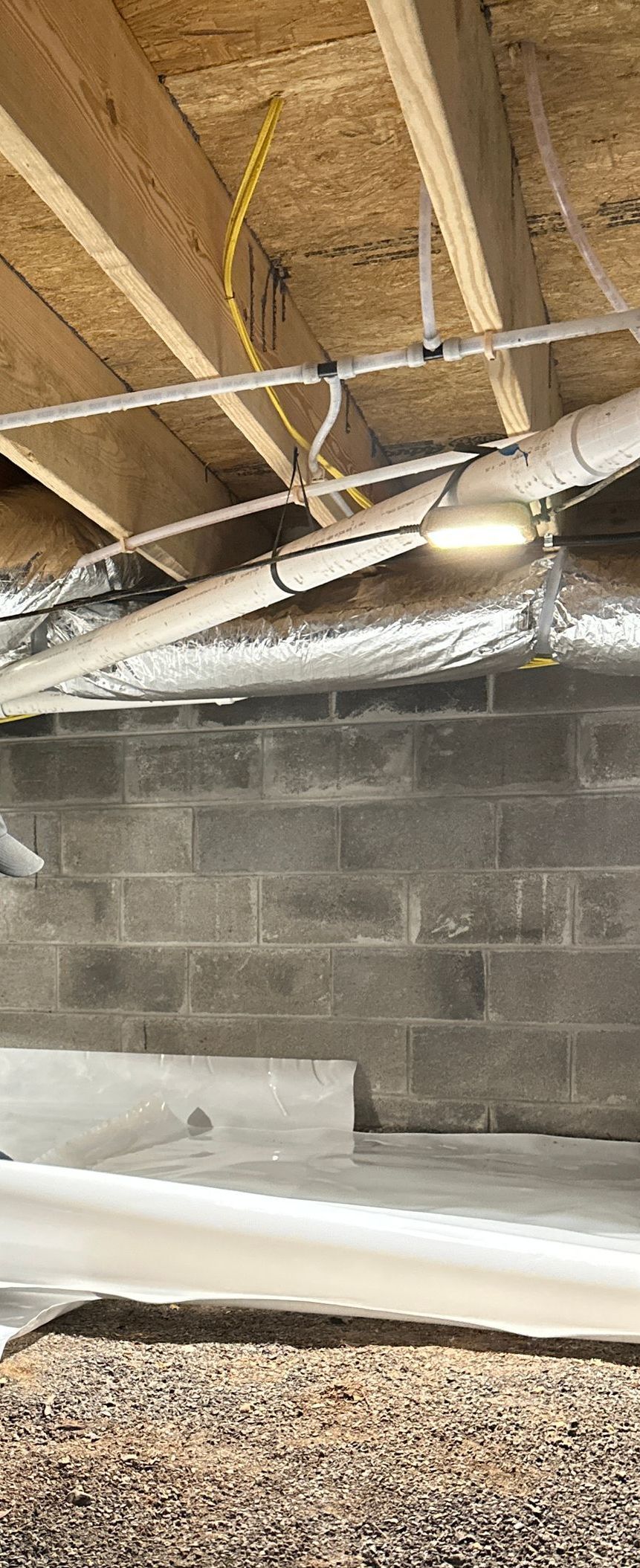 A basement with a lot of pipes and wires hanging from the ceiling.