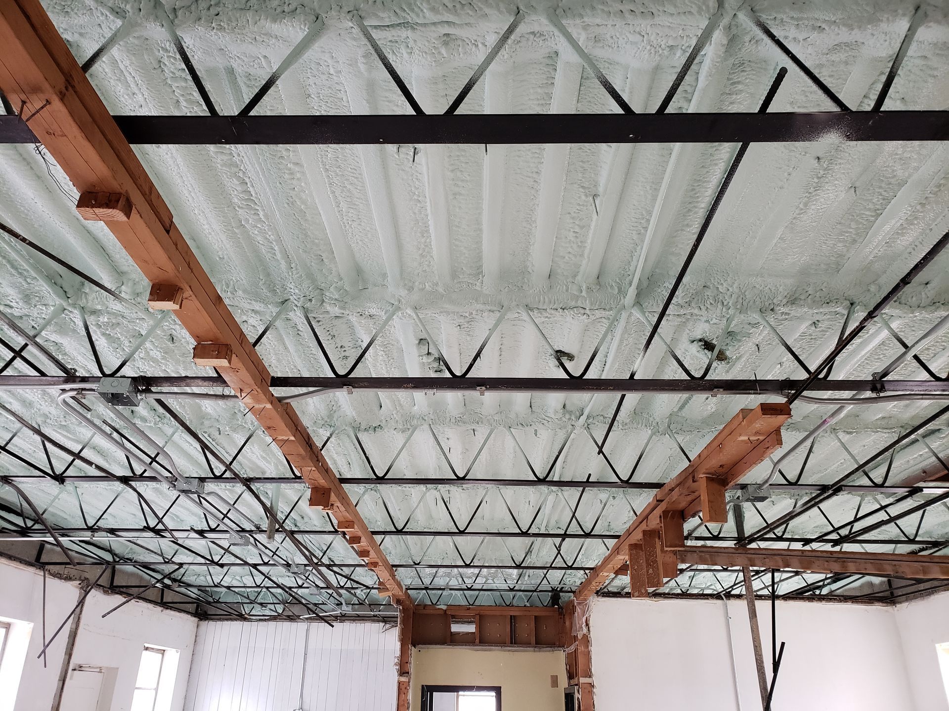 The ceiling of a metal building with spray  foam on it.