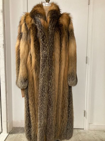 A fur coat is hanging on a mannequin in front of a door.
