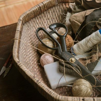 A wicker basket filled with sewing supplies including scissors and yarn.