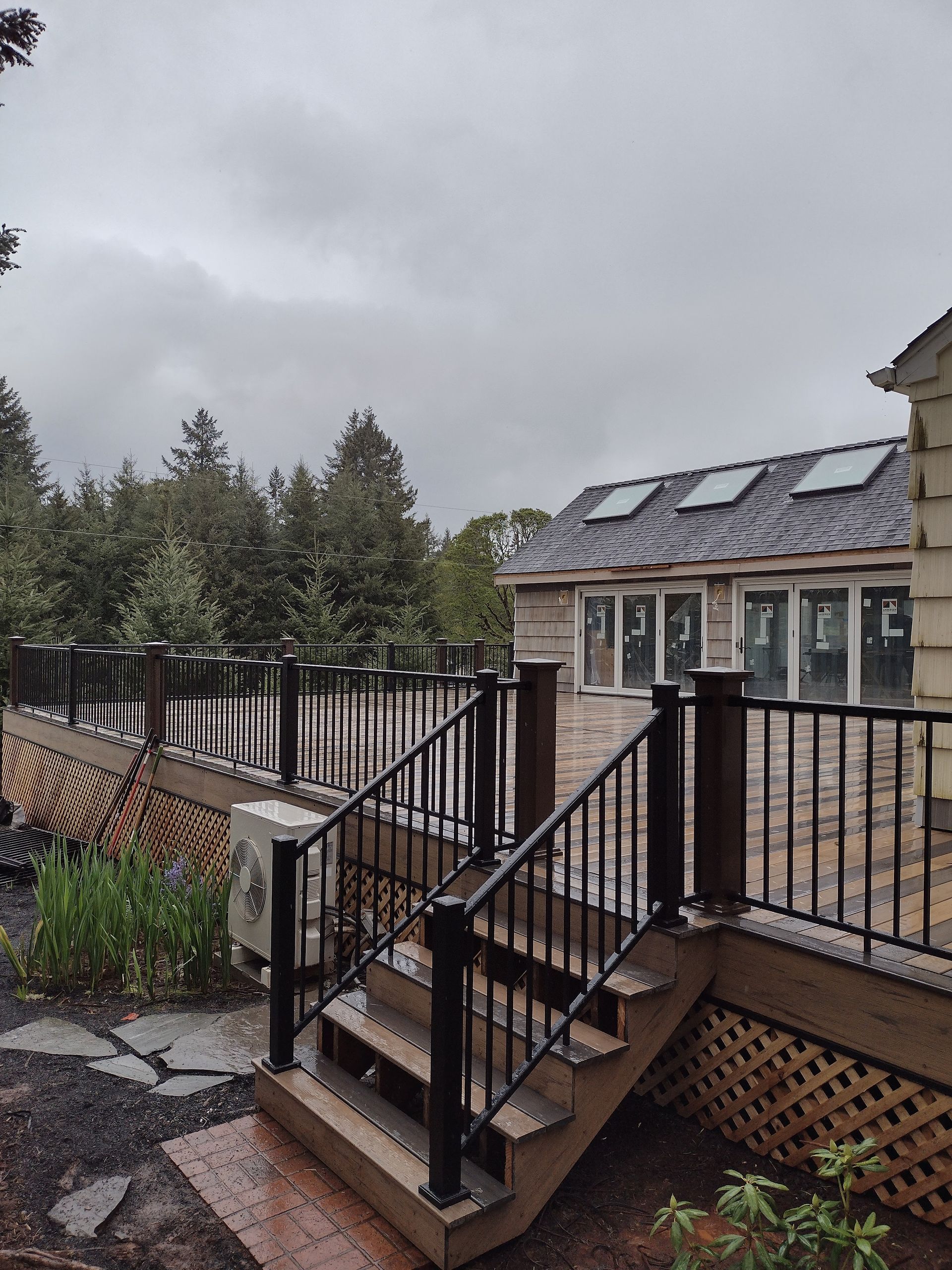 Rainy outdoor staircase leading to a brick building with a metal fence and trees nearby