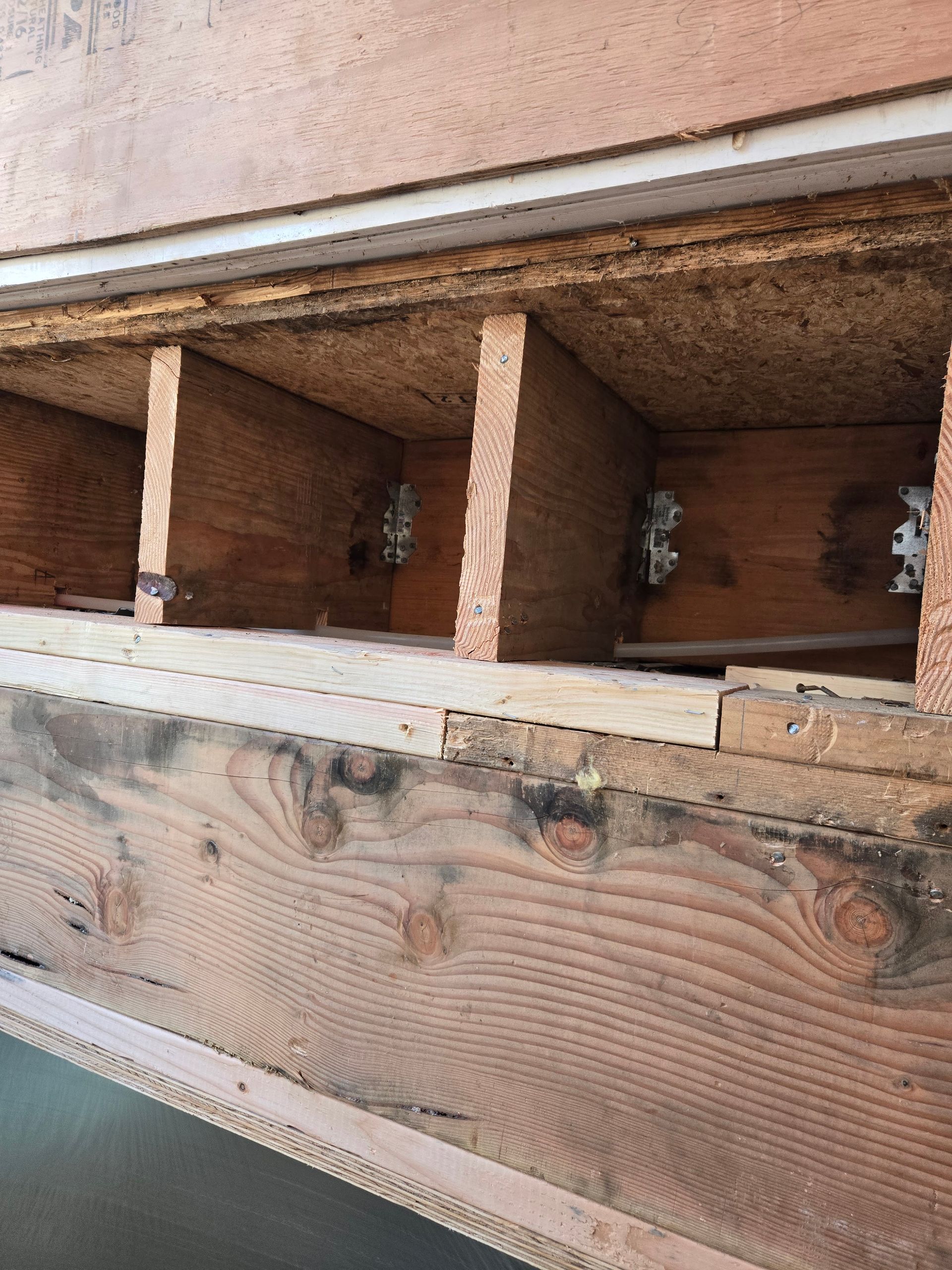 Close-up of a wooden structure with rectangular openings and visible bolts and grain.