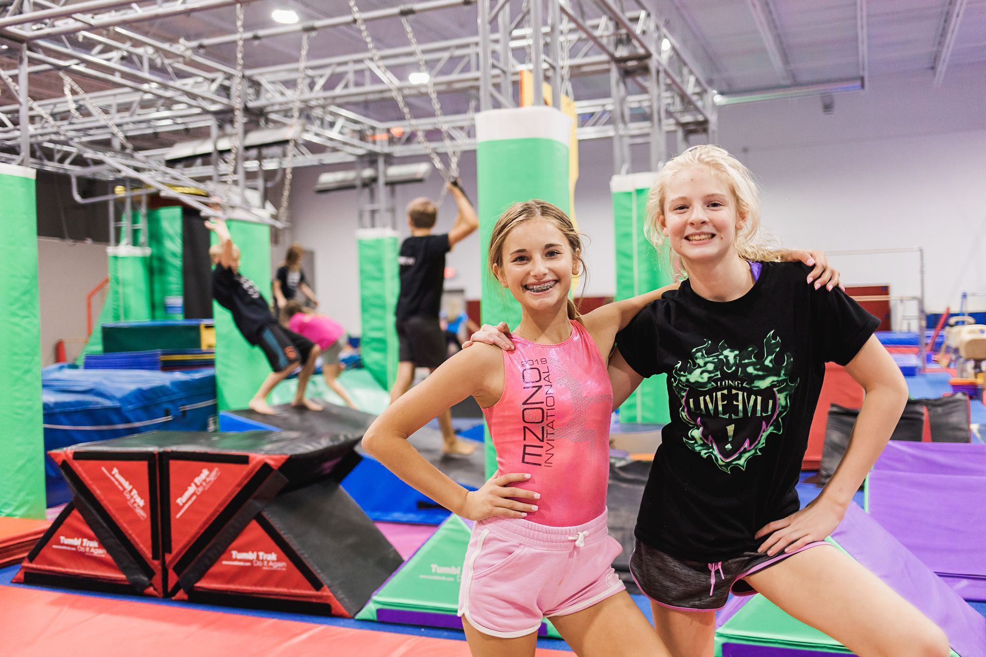 Two young girls are posing for a picture in a gym.