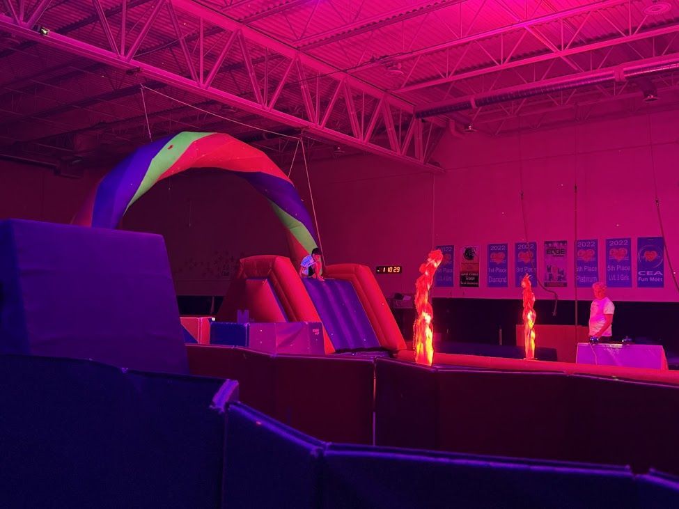 A trampoline park is lit up with glow in the dark lights.