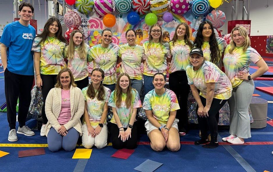 A group of people wearing tie dye shirts are posing for a picture.
