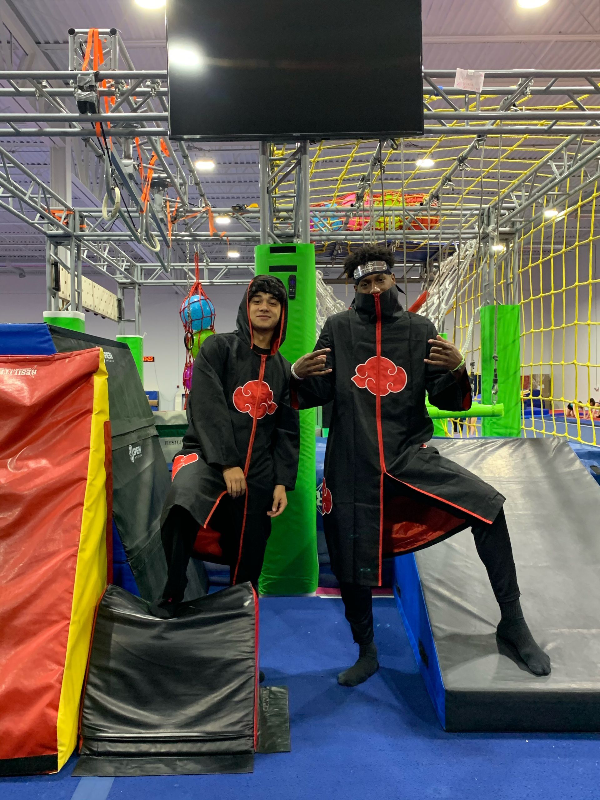Two men in ninja costumes are posing for a picture in a gym.