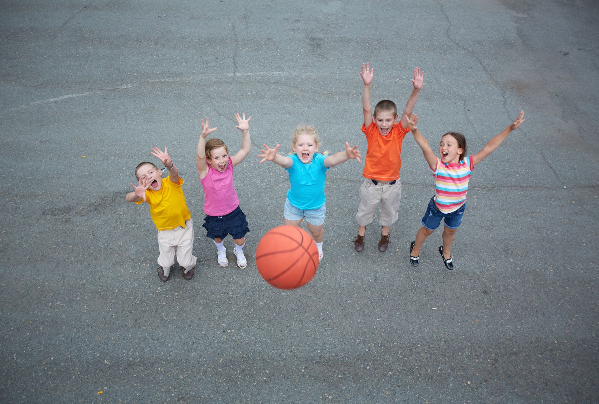 A group of children are playing with a basketball on a court.