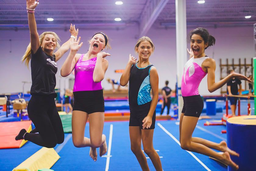 A group of young girls are jumping in the air in a gym.