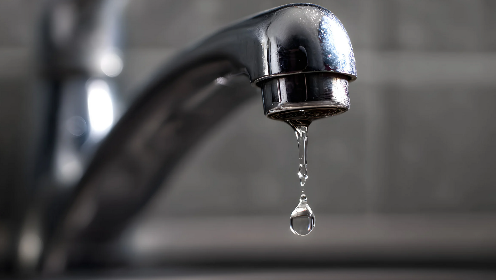Chrome faucet dripping water.