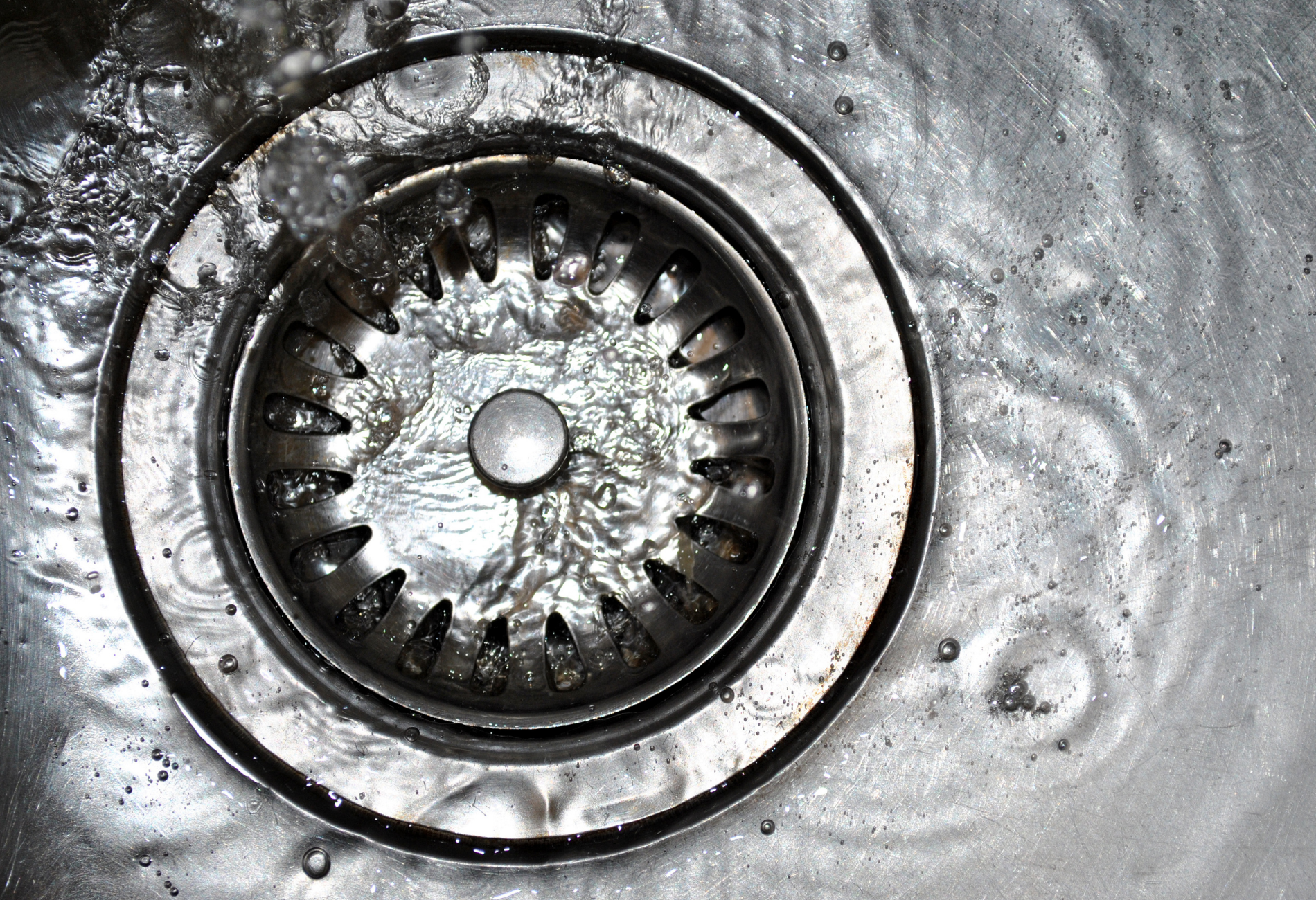 Water flows into a stainless steel sink drain.