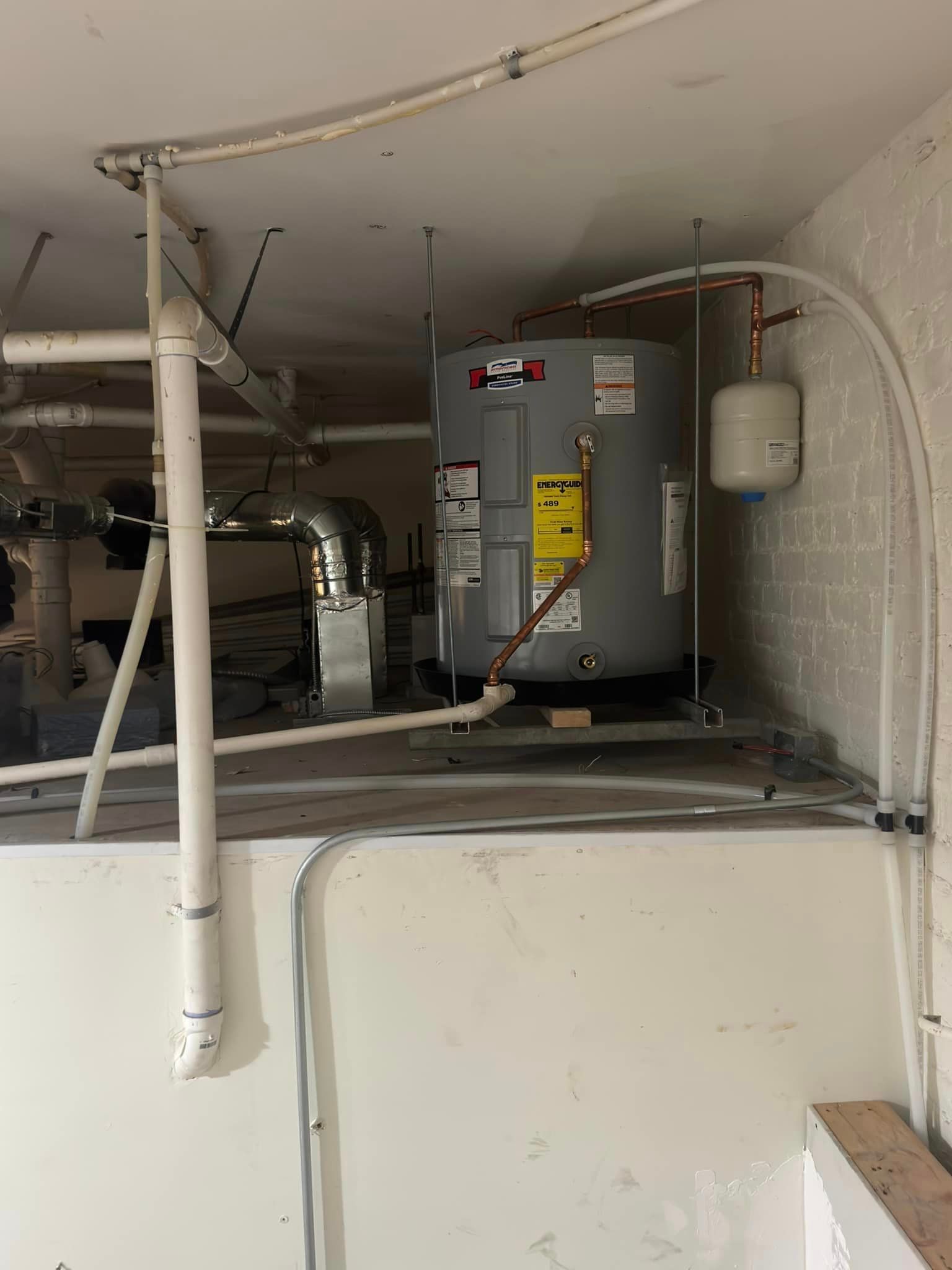A water heater is hanging from the ceiling in a basement.