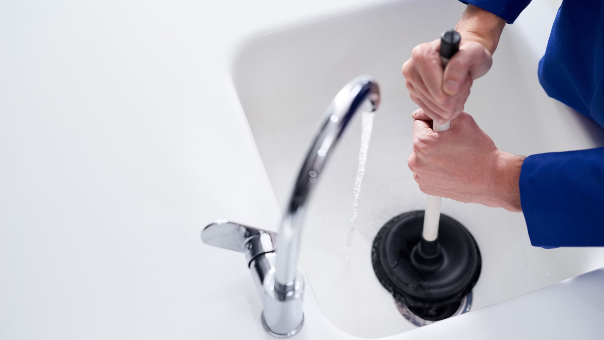 A person is using a plunger to drain a sink.