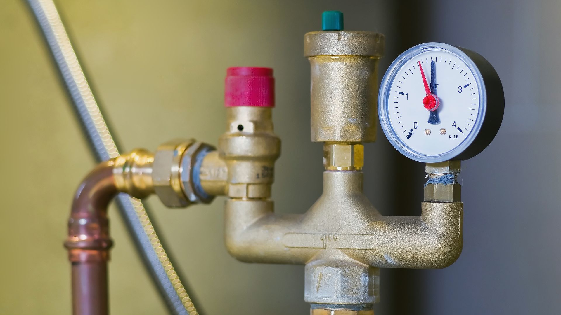 A close up of a brass pipe with a pressure gauge attached to it.