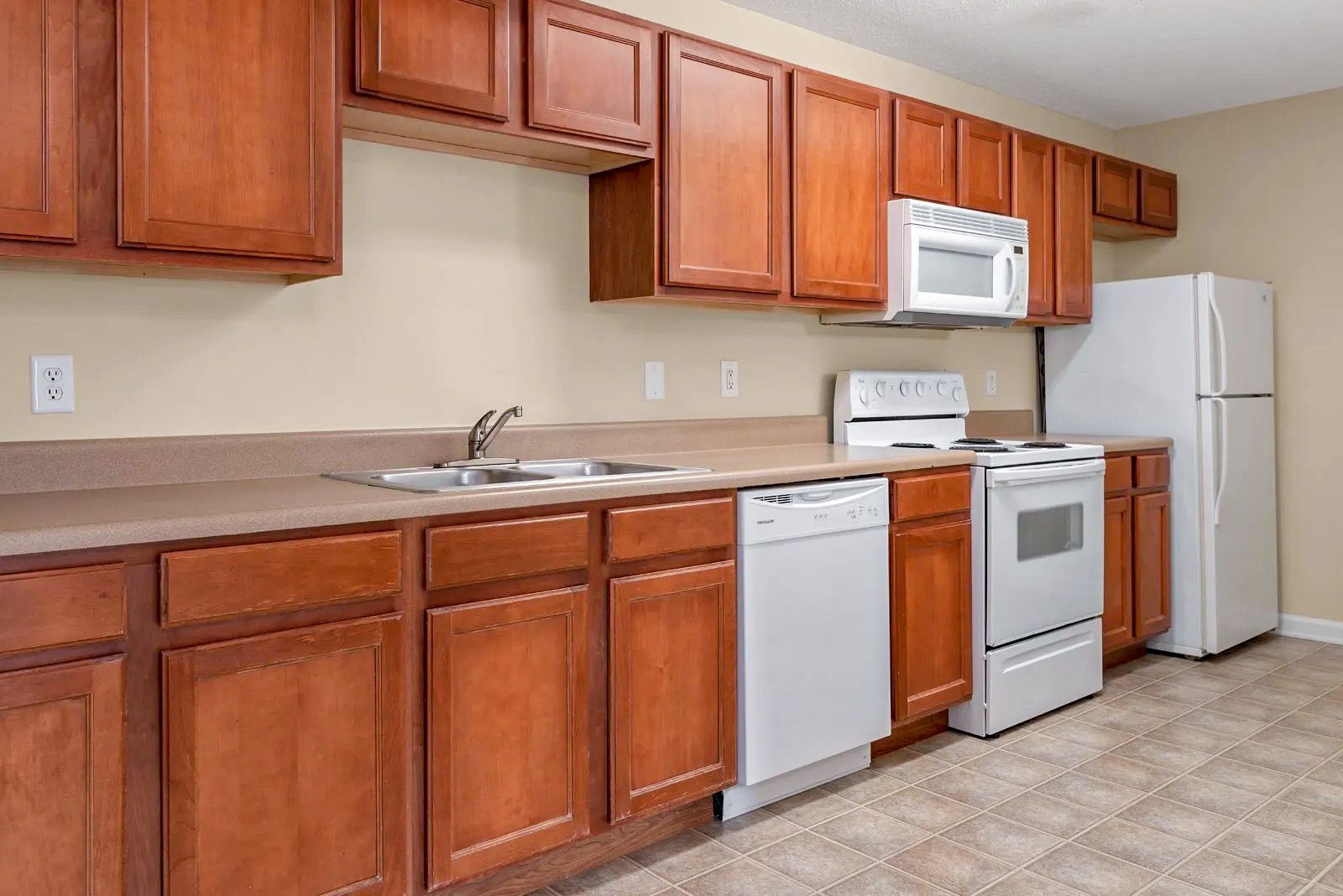 Kitchen with wood cabinets, light countertops, and white appliances.