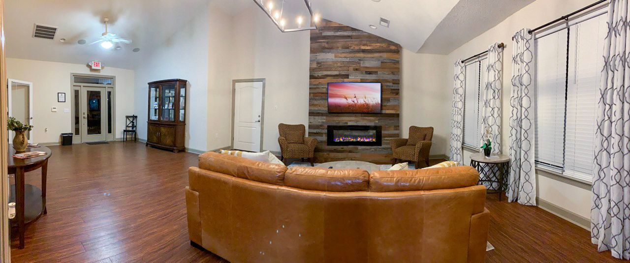 Large living room with fireplace, leather couch, and windows with patterned curtains.