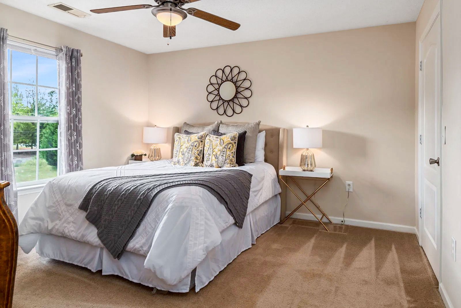Bedroom with bed, nightstands, and window with curtains. Neutral color scheme and decorative accents.