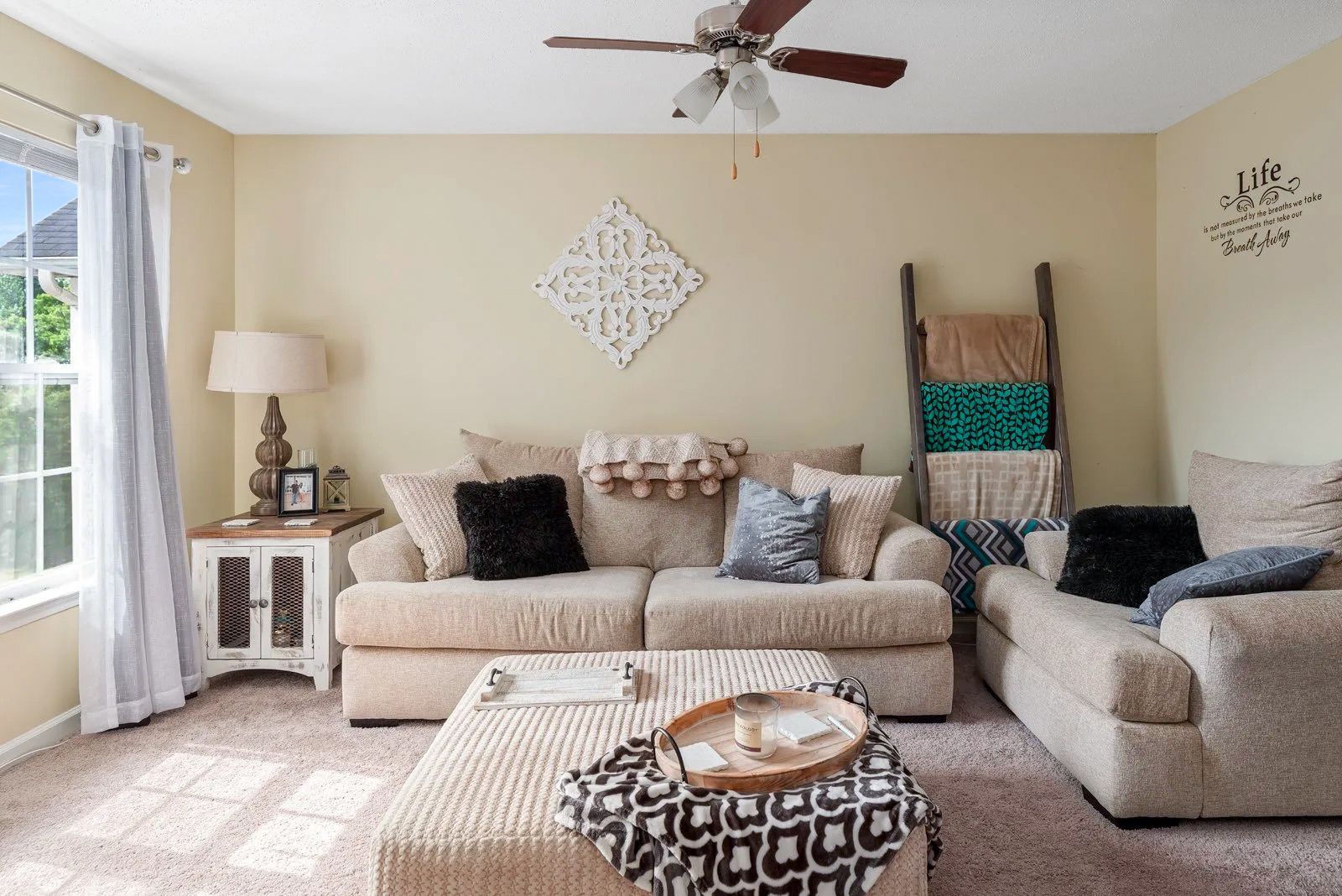 Living room with tan walls, beige sofa, and decorative ladder.