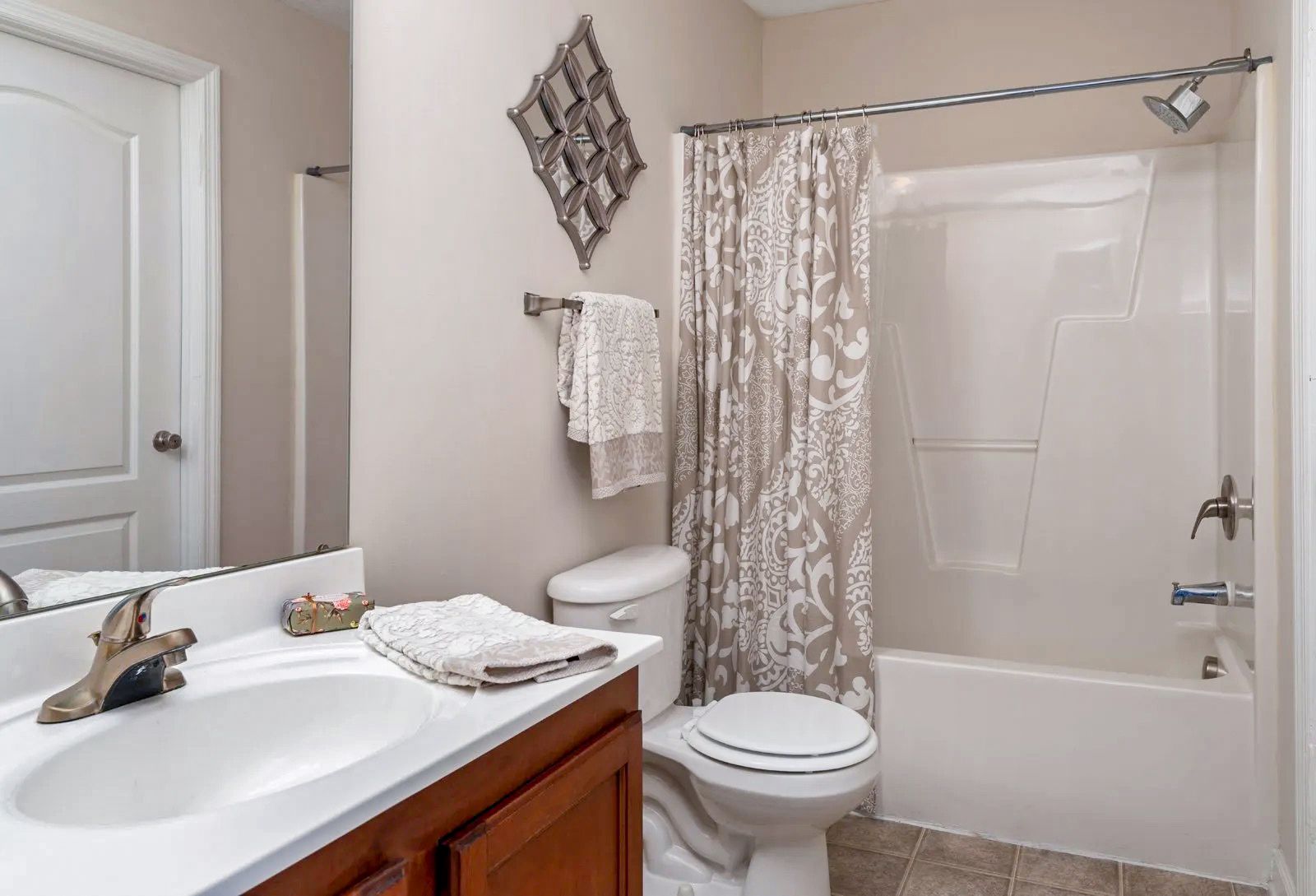 Bathroom with a sink, toilet, tub, and decorative wall art. Beige walls and a white door.