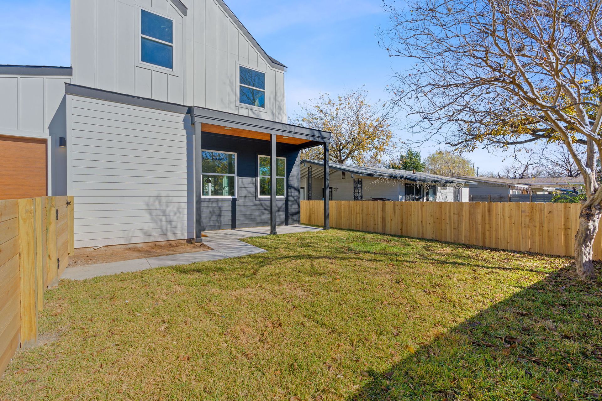 the backyard of a house with a wooden fence and a large lawn .