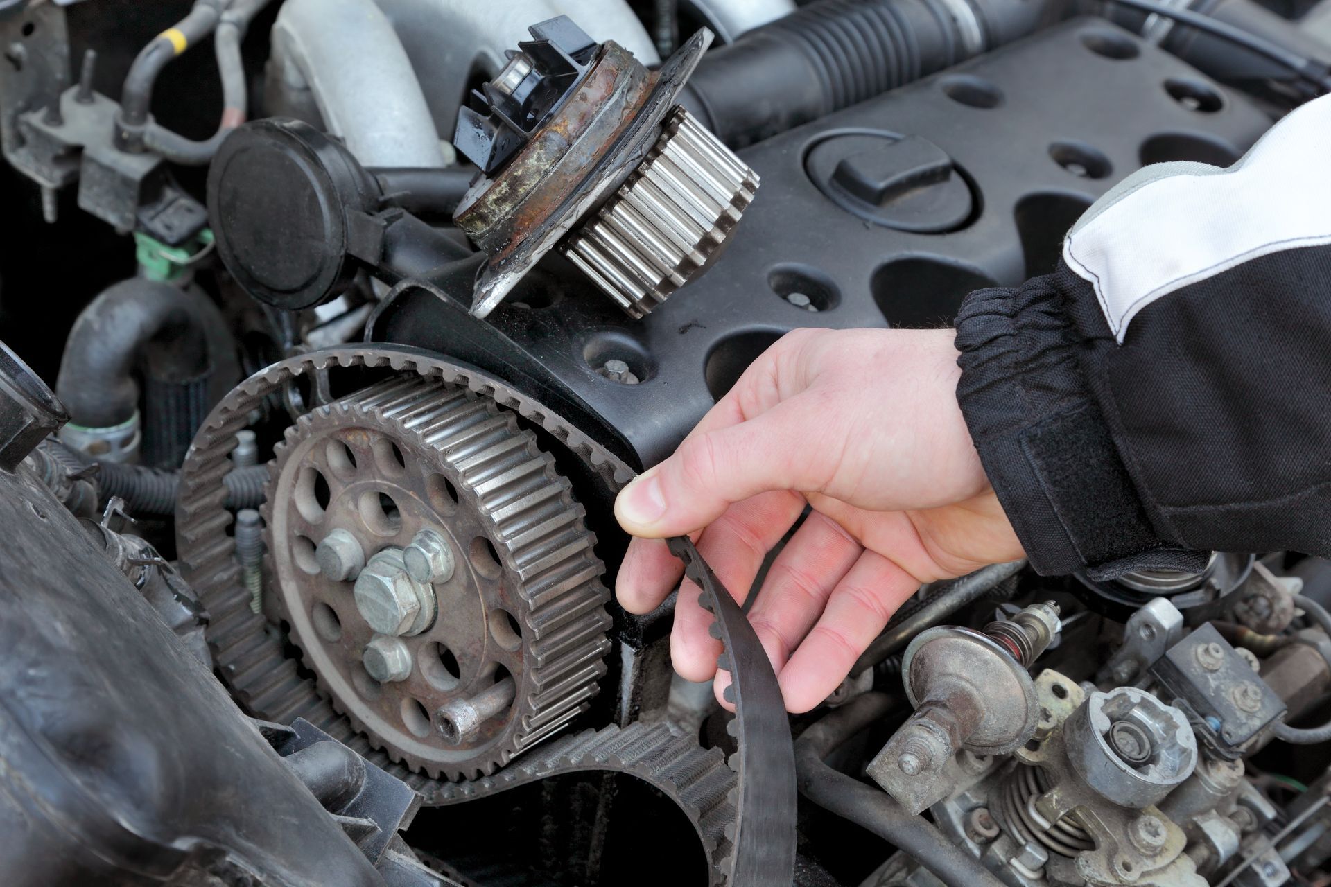 A person is cleaning a timing belt on a car engine.   | The Kar Shop