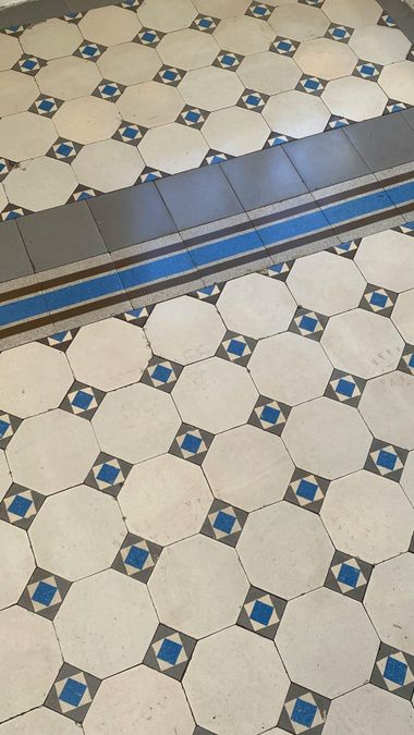 Patterned tile floor with a blue metal threshold strip across the center