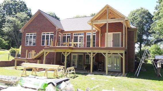A large brick house with a wooden deck under construction.