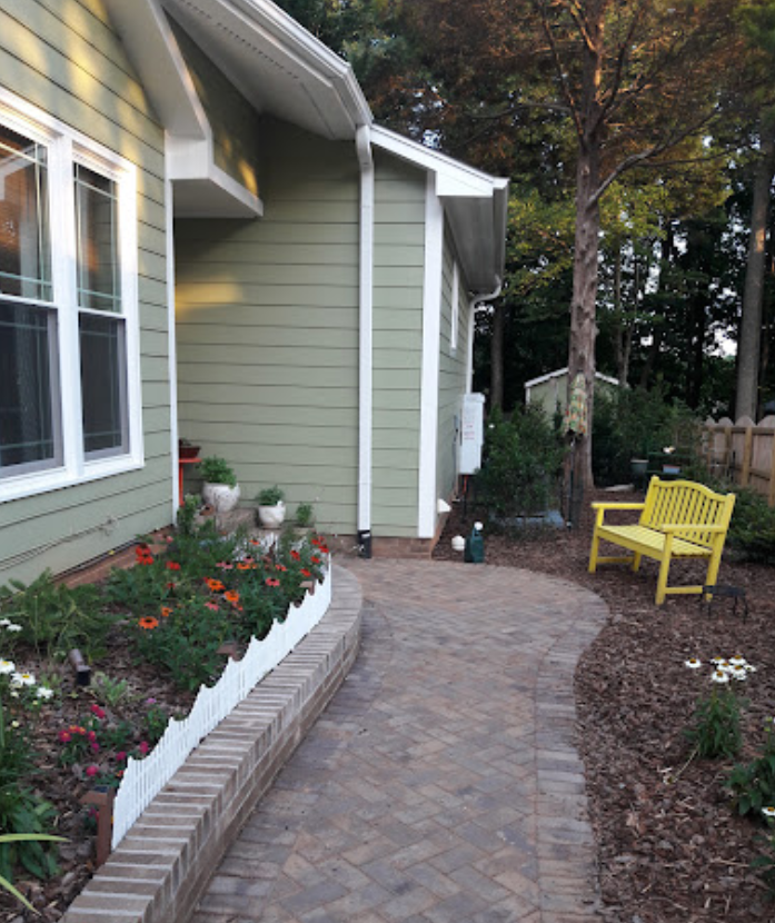 A yellow bench sits in front of a green house