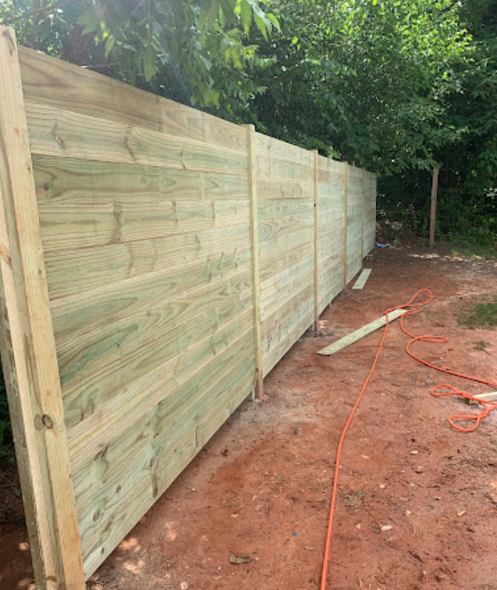 A wooden fence is being built in a backyard.