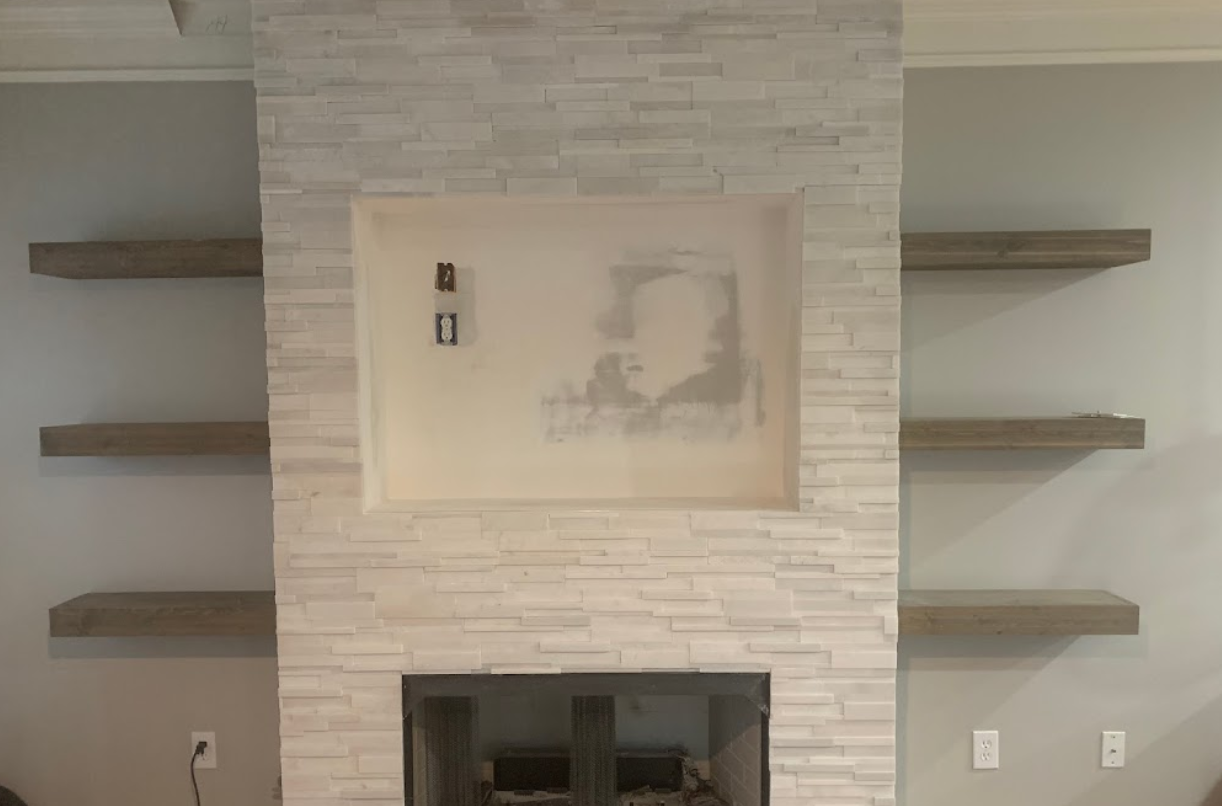 A living room with a fireplace , shelves and a picture on the wall.