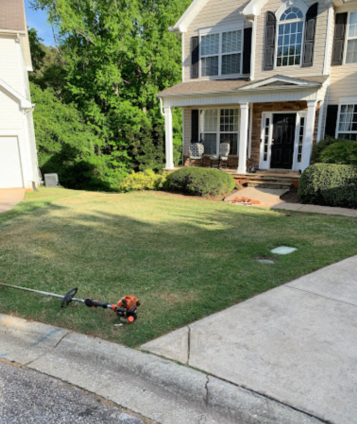 A lawn mower is sitting on the grass in front of a house.
