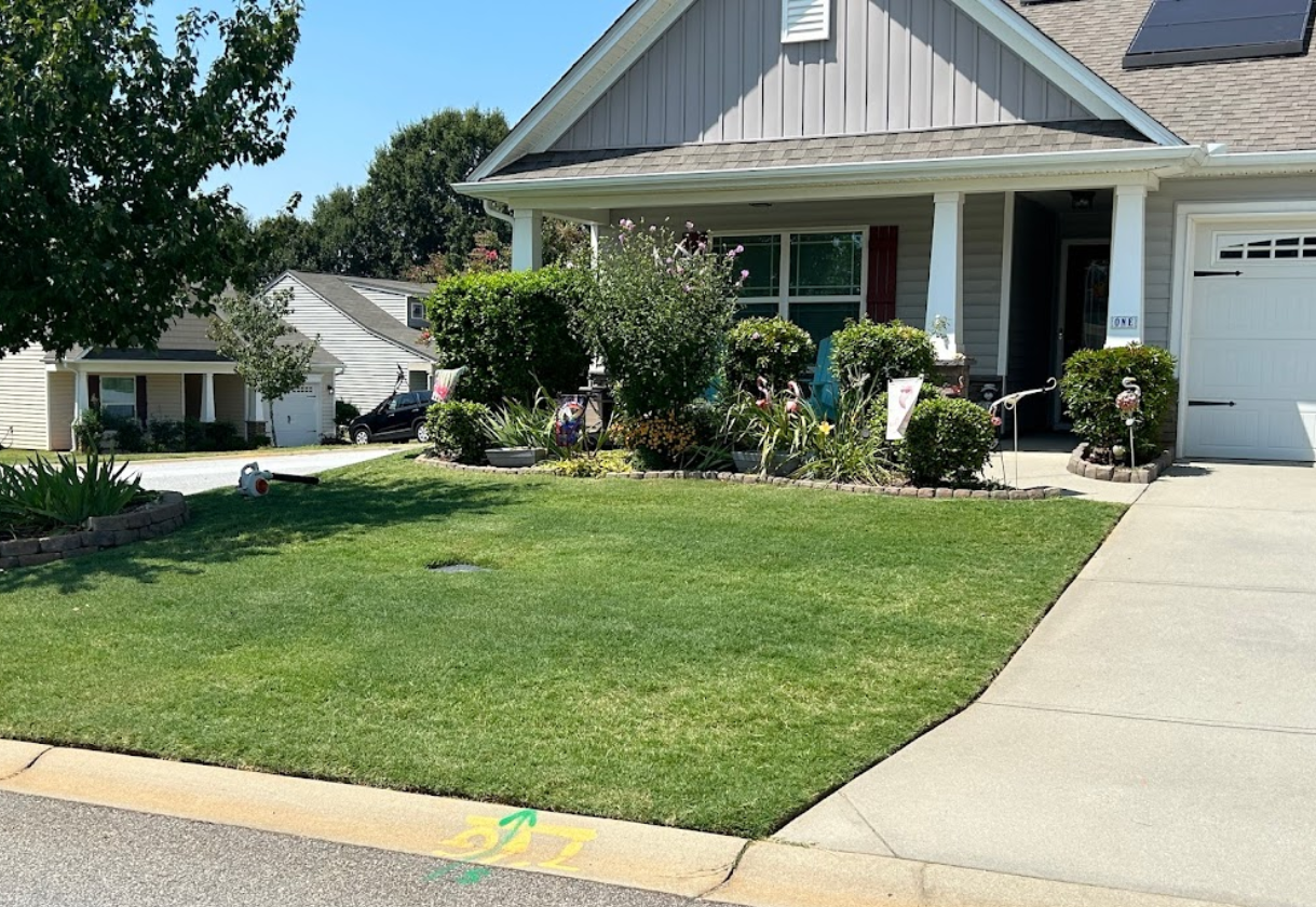 A house with a lush green lawn and a white garage door.