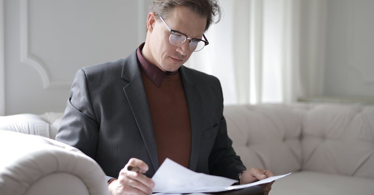 Man looking over documents while sitting on a couch. 