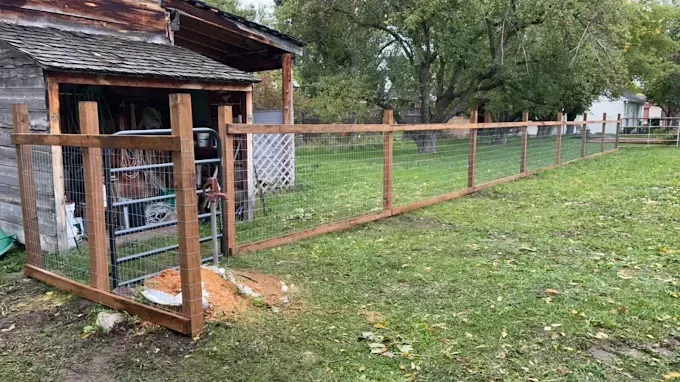 A wooden fence is being built in the backyard of a house.