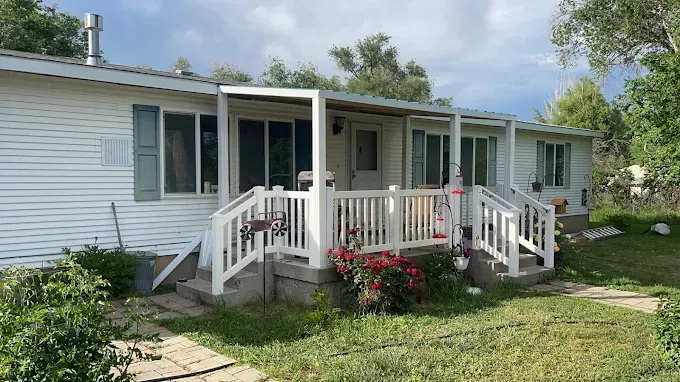 A white mobile home with a porch and stairs.