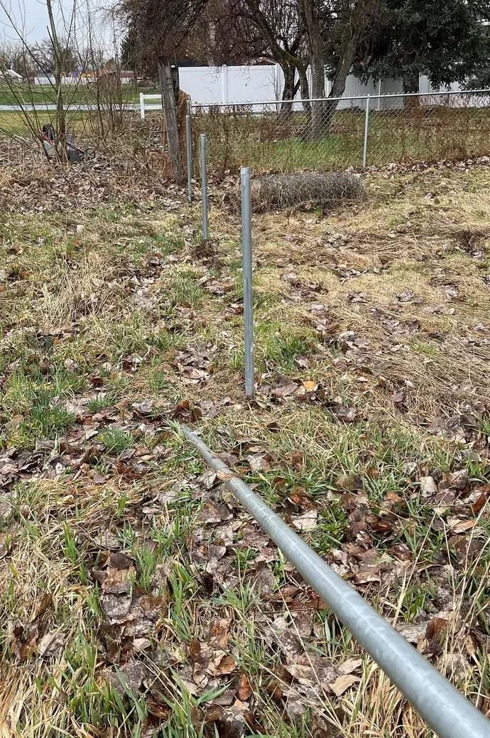 A metal pole is sitting in the middle of a grassy field.