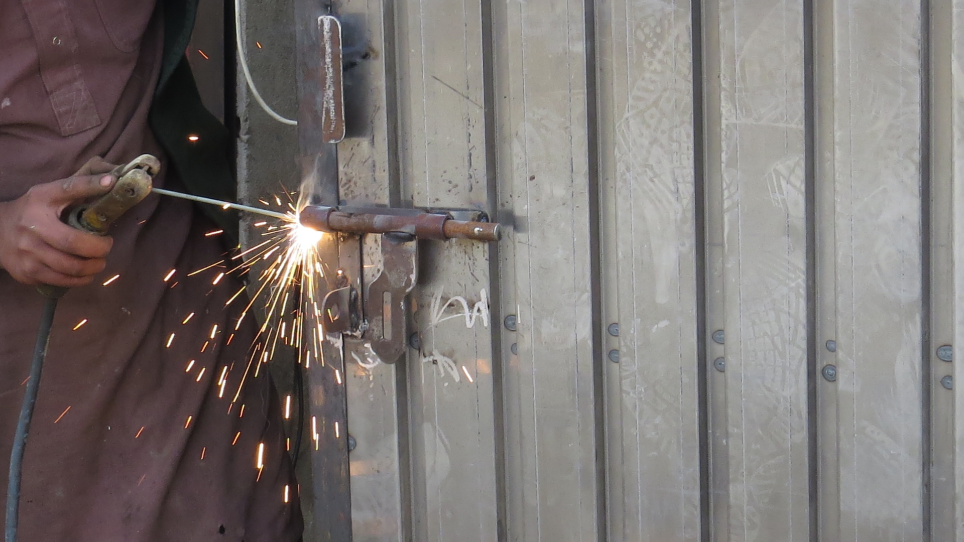 A man is welding a door with sparks coming out of it