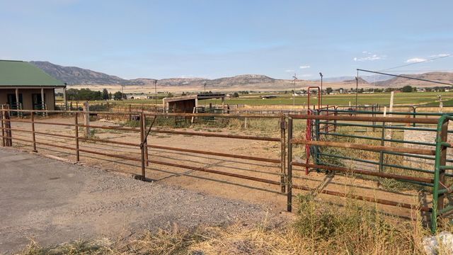 A white fence with rocks in front of it and trees in the background.