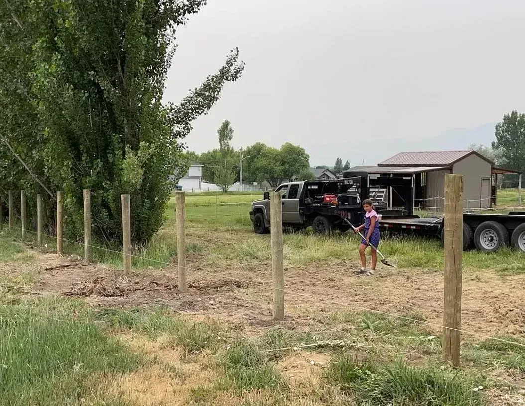 A man is standing in a field next to a trailer.