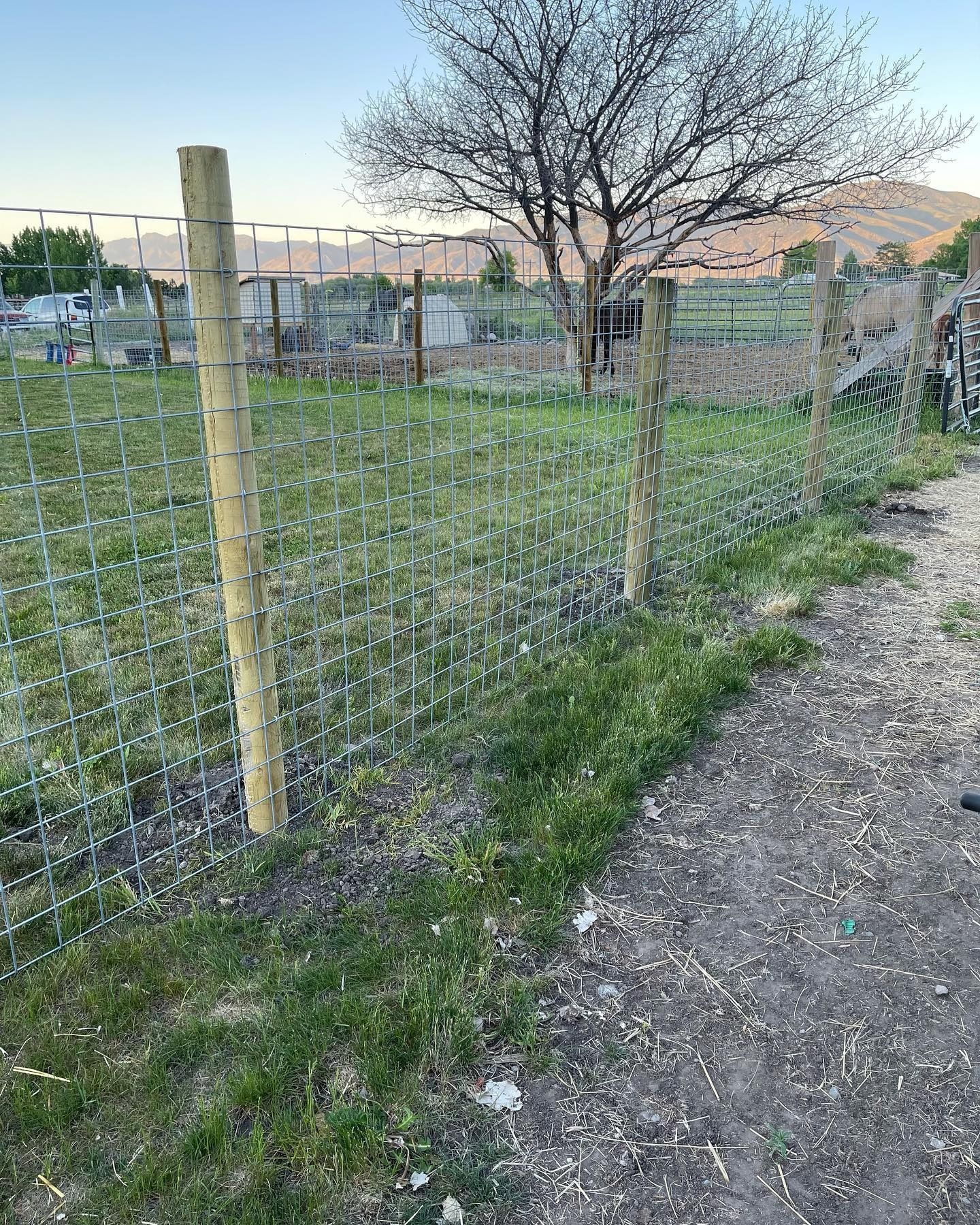 A fence with a wooden post in the middle of a field.