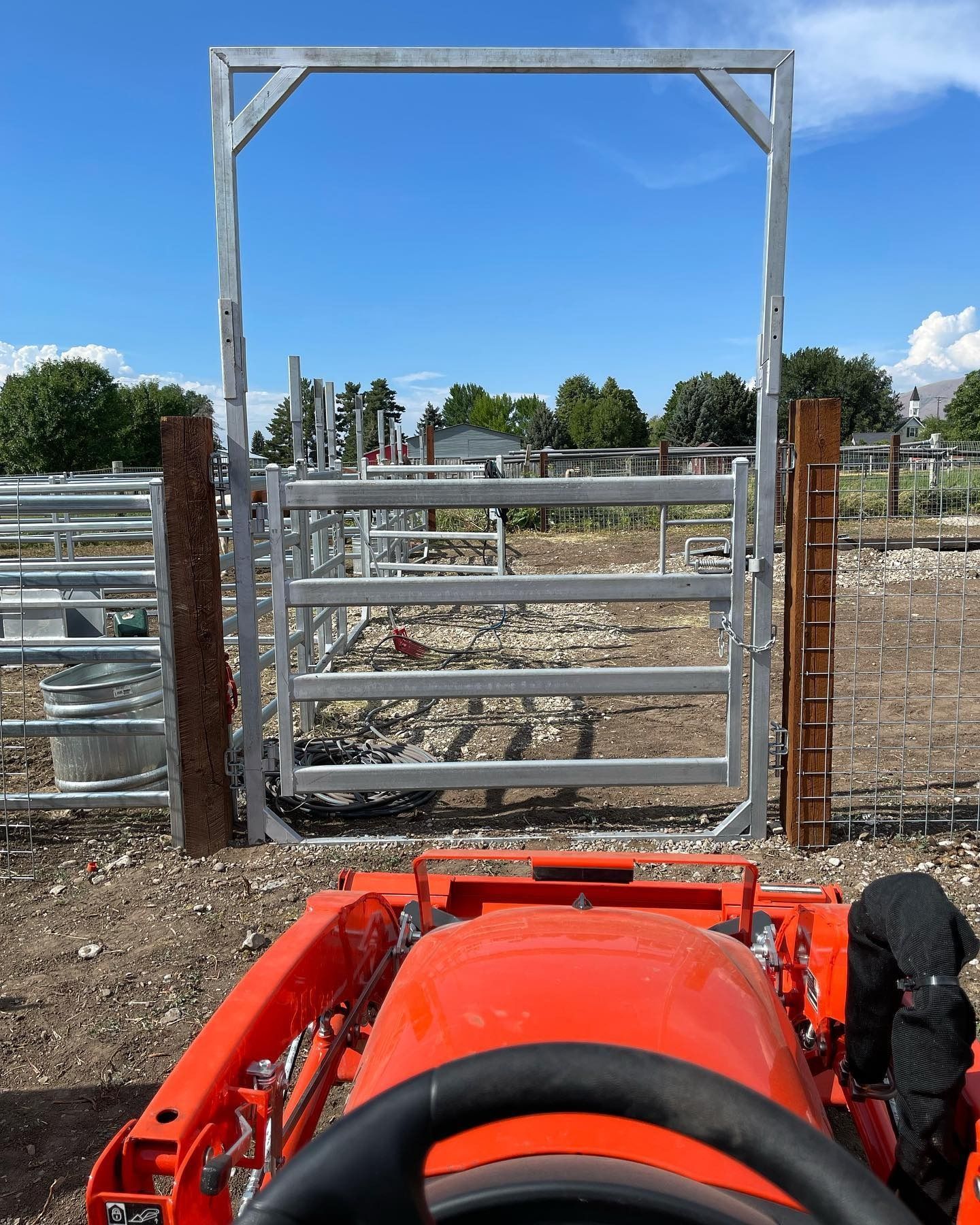An orange tractor is parked in front of a metal gate