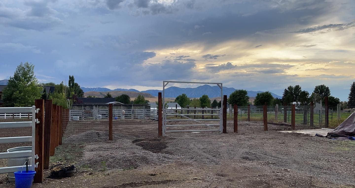 A fenced in area with mountains in the background and a blue bucket in the foreground.