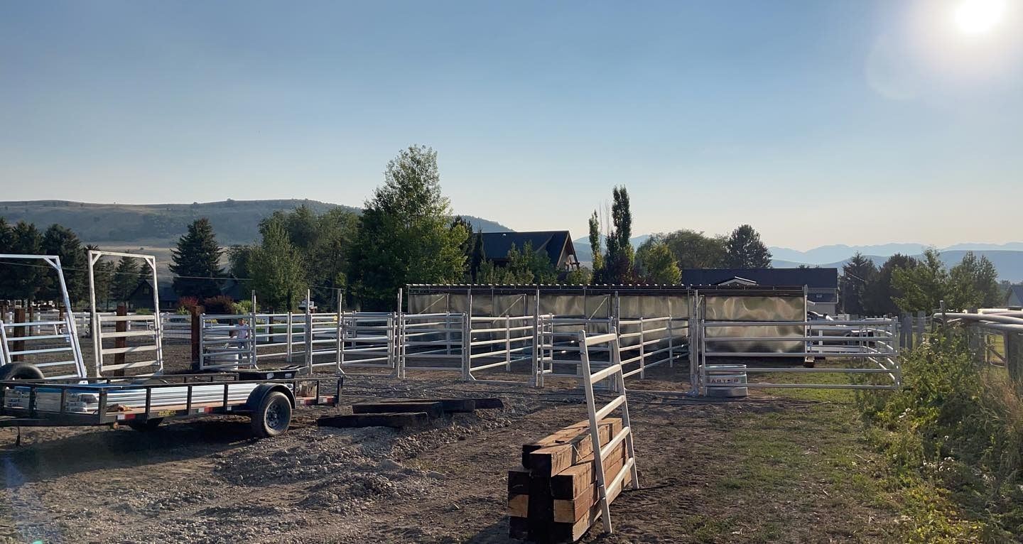 A dirt field with a lot of fences and trees in the background.