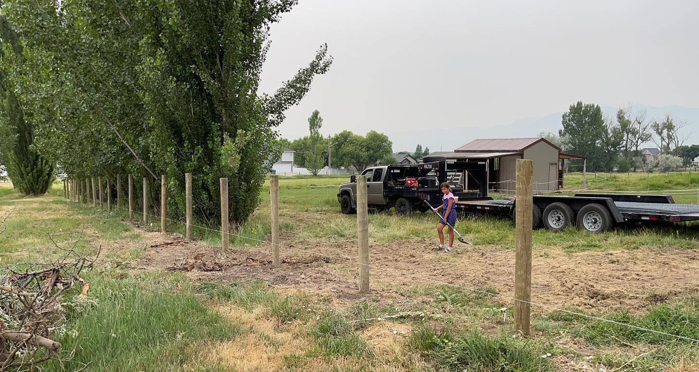 A man is standing in a field next to a trailer.