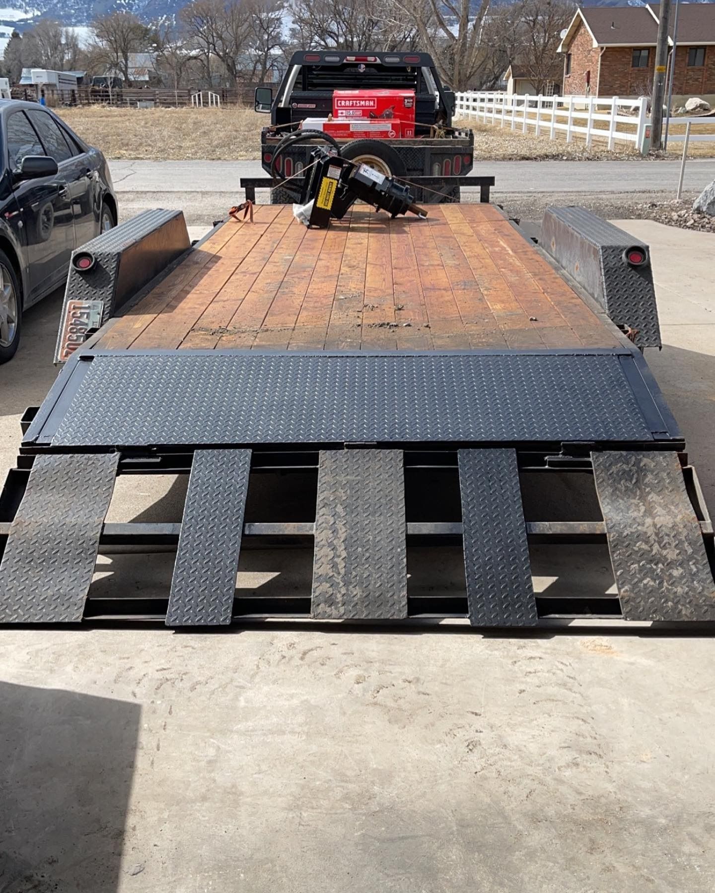 A red truck is parked behind a trailer with a motorcycle on it